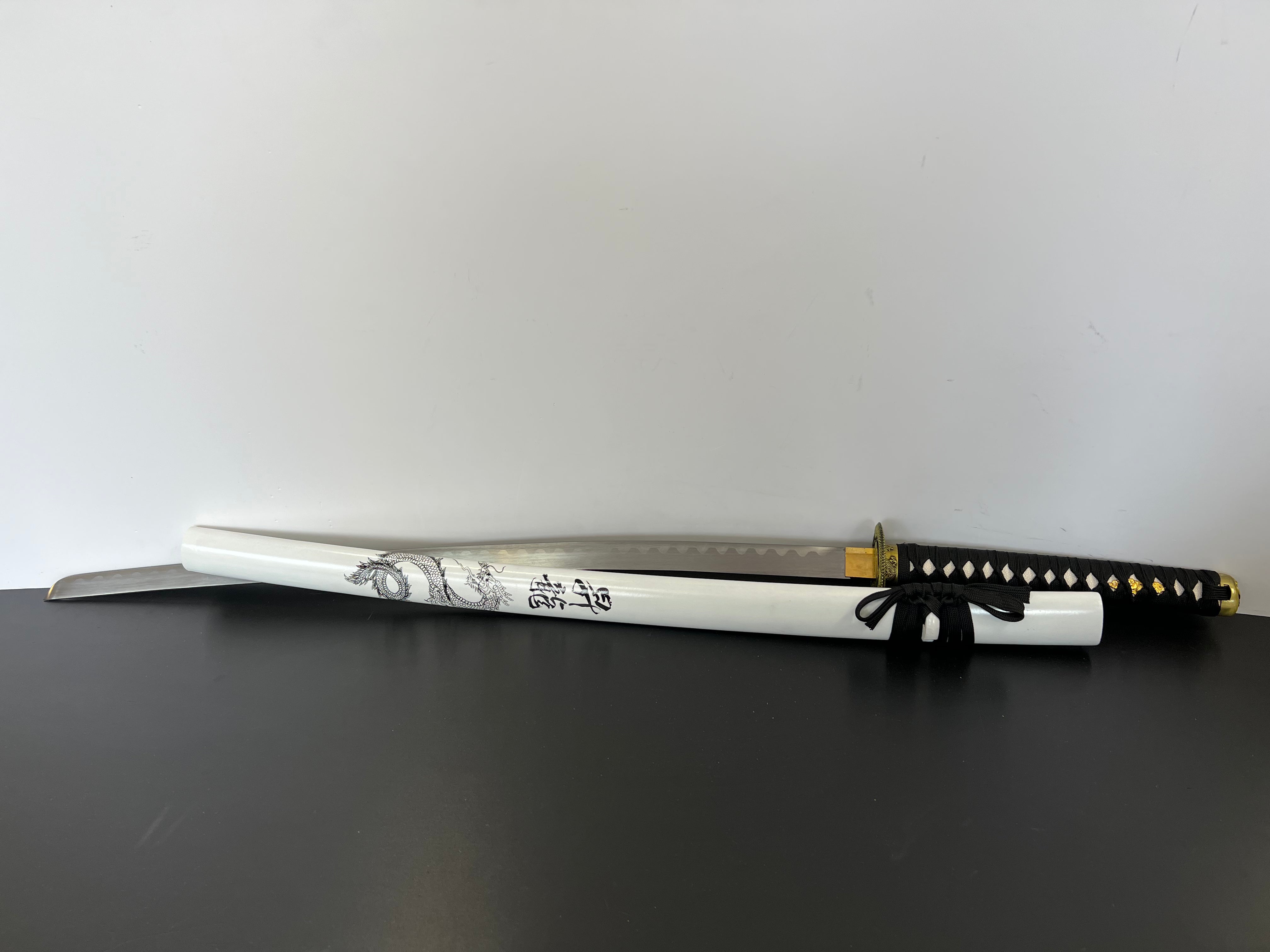 Ein Katana mit Drachenmuster, welche nicht nur auf der Saya (Schwertscheide) zu sehen ist, sondern auch auf der Tsuba. Die Tsuba hat die Form eines Drachen, welche im Japanischen Stil Illustriert ist. Die Katana ist das traditionelle Schwert der Japaner und ist aufgrund der einzigartigen Form leicht wiederzuerkennen.